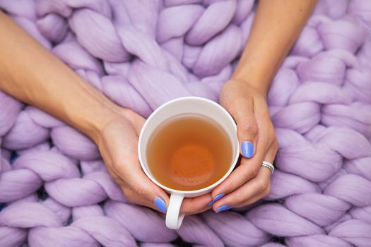 A girl wrapped in a large pink merino wool blanket, a warm and very soft blanket, a girl holding a cup of hot white tea, top view