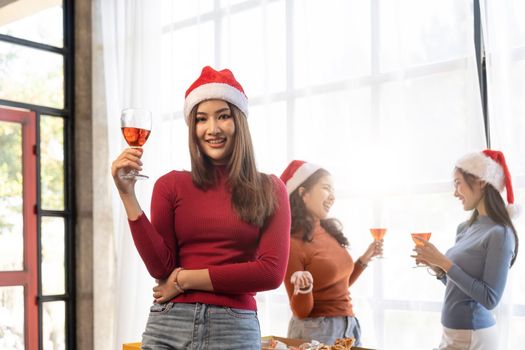 Group of Asian friends gather to celebrate Christmas with champagne and eating pizza at home. Joy of holiday party with friends or colleague concept.