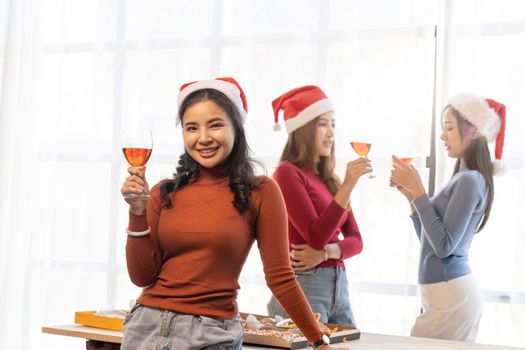 Group of Asian friends gather to celebrate Christmas with champagne and eating pizza at home. Joy of holiday party with friends or colleague concept.