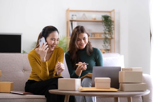 Portrait of Starting small businesses SME owners, two Asian woman check online orders Selling products working with boxs freelance work at home office, sme business online small medium enterprise.