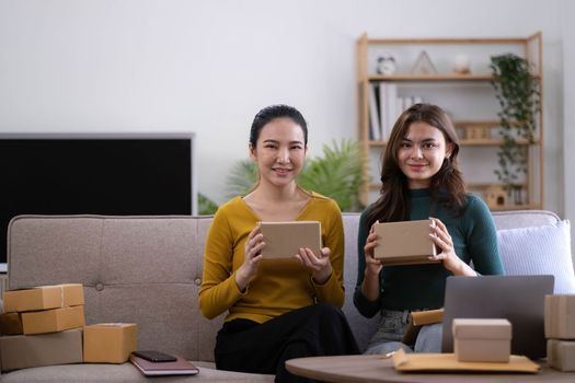 Portrait of Starting small businesses SME owners, two Asian woman check online orders Selling products working with boxs freelance work at home office, sme business online small medium enterprise.