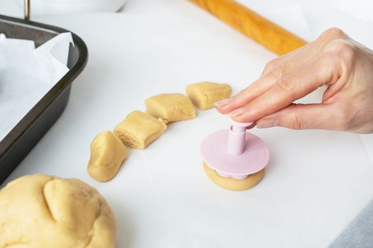 The process of making cookies with shapes in the form of flowers, a rolling pin and a tray, the concept of cooking, baking at home