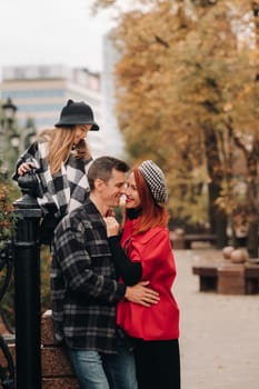 A stylish family of three strolls through the autumn city posing for a photographer . Dad, mom and daughter in the autumn city.