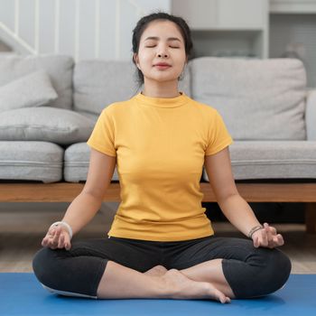 Young asian woman doing yoga exercise indoors at home, meditating.