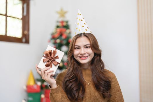 Portrait of smiling asian woman with Christmas gift at home.