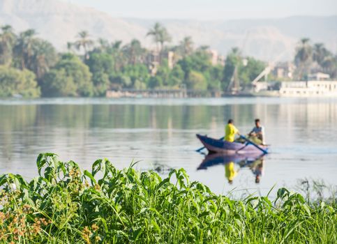 Traditional egyptian bedouin fisherman in rowing boat on river Nile fishing by riverbank