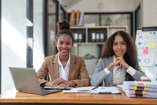 Two young Asian business woman talk, consult, discuss working with new startup project idea presentation analyze plan marketing and investment in the office..