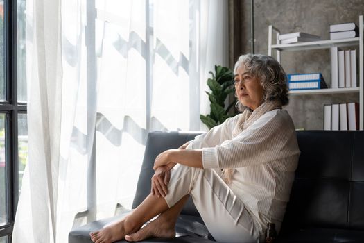 Sad tired ill sick lonely disappointed caucasian old elderly senior woman grandmother sitting on the sofa couch, feeling nostalgy, pain, missing grandchildren, bankruptcy, fraud at home.