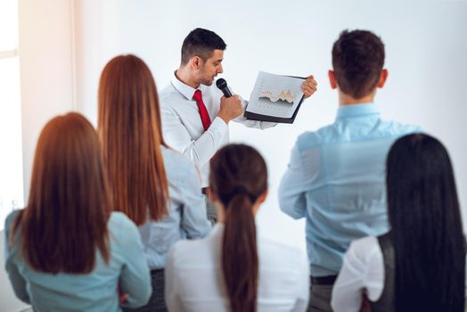 Businesspeople having meeting in a office. Young businessman standing in front of flip chart and having presentation.