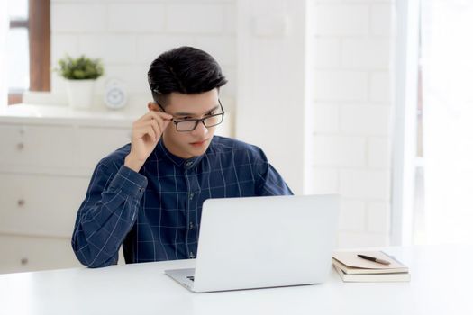 Young business man in glasses working from home with laptop computer on desk, freelance male sitting stay home using notebook for communication on table, entrepreneur in startup business, new normal.