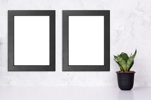 Mockup black frame vertical on the wall and plants in pot on table top at home, mock up poster for presentation on desk, your design for gallery photo and picture, border template for advertising.