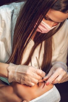 Beautician applying japanese method of drawing on eyebrows to model.  