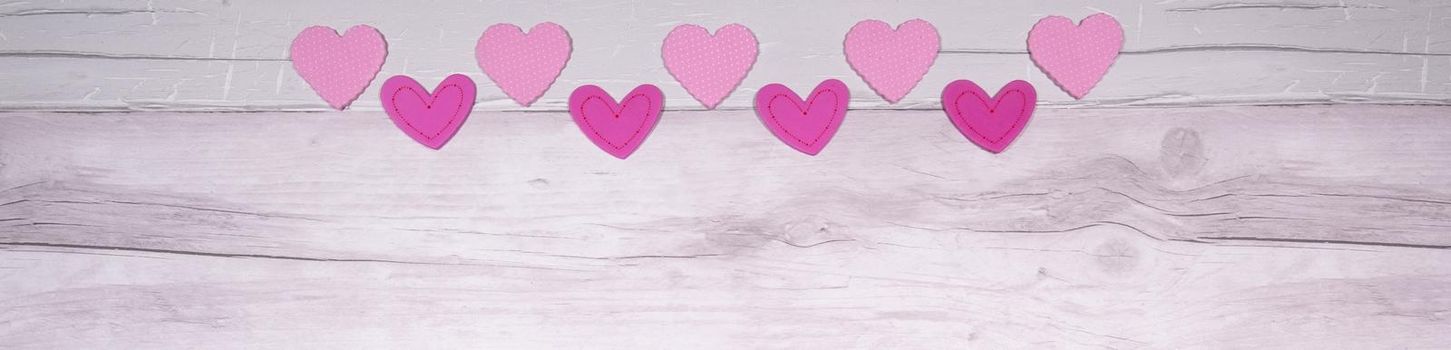 Pink felt hearts on a background of old wooden planks resembling an old parquet floor. Concept of valentines day and love in general.