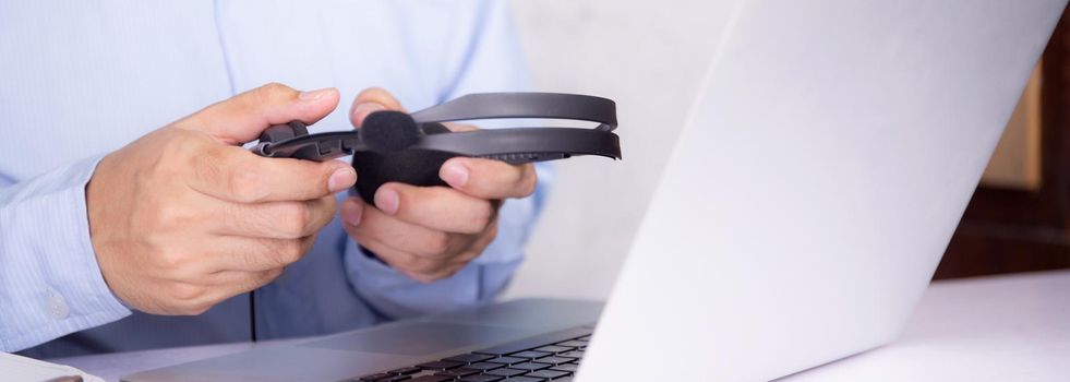 Hands of man holding headphone while laptop computer on desk, e-learning online, webinar for education and learning, digital seminar with notebook, video conference, headset for course multimedia.