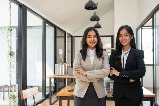 Happy two beautiful young Asian businesswoman standing discuss working together at office..