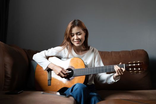 Image of happy beautiful woman playing guitar and composing song.