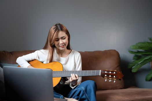 Image of happy beautiful woman playing guitar and composing song.