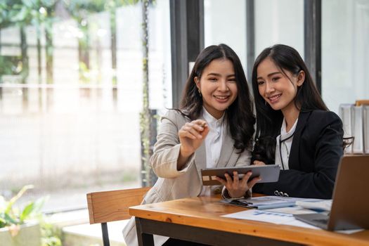 Two young Asian businesswoman discuss investment project working and planning strategy. Business people talking together with laptop computer at office..