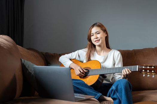 Image of happy beautiful woman playing guitar and composing song.