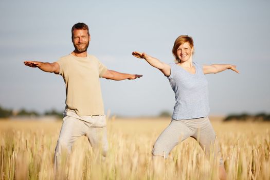 Yoga is part of their lifestyle. a mature couple in the warrior position during a yoga workout in a field
