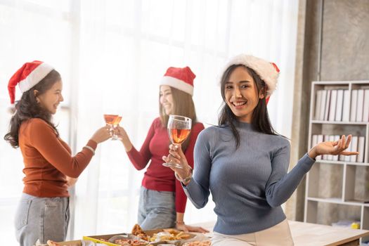 Group of Asian friends gather to celebrate Christmas with champagne and eating pizza at home. Joy of holiday party with friends or colleague concept.