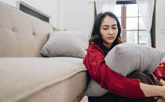 Unhappy asian pretty young woman siting alone on couch with feeling sadness.