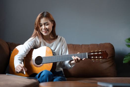 Image of happy beautiful woman playing guitar and composing song