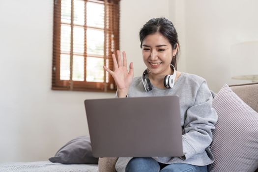 Friendly woman waving her hand in online meeting.