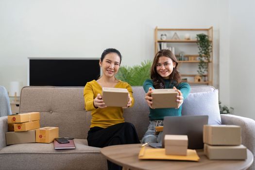 Young business woman working online e-commerce shopping at her shop. Young woman seller prepare parcel box of product for deliver to customer. Online selling, e-commerce