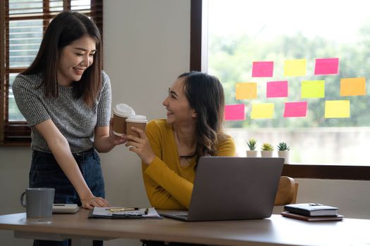 Two young Asian business woman talk, consult, discuss working with new startup project idea presentation analyze plan marketing and investment in the office..