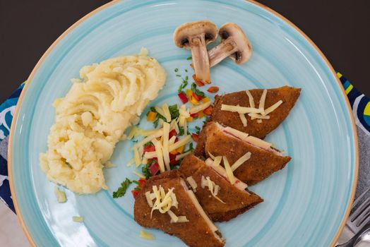 Stuffed chicken panne a la carte meal with mushrooms and mashed potato at restaurant table setting