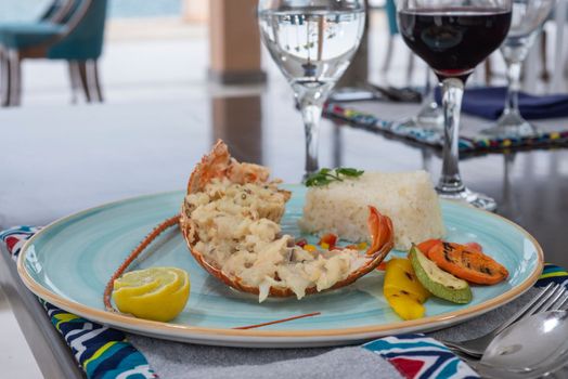 Stuffed lobster dish a la carte meal with white rice and vegetables at restaurant table setting