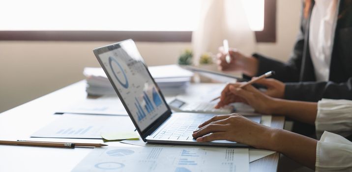 Group of business people colleagues working for financial analysis on laptop while sitting at the office desk