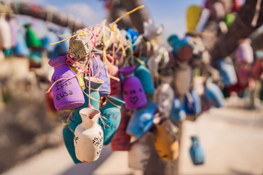 Wish tree. Small multi-colored jugs with inscriptions, wishes hanging on the branches of a tree., against the backdrop of sand ruins and blue sky.