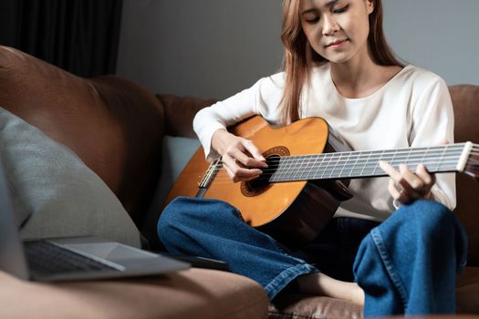 Image of happy beautiful woman playing guitar and composing song.