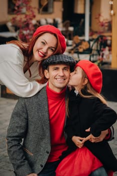 A stylish family of three strolls through the autumn city posing for a photographer . Dad, mom and daughter in the autumn city.