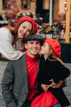 A stylish family of three strolls through the autumn city posing for a photographer . Dad, mom and daughter in the autumn city.