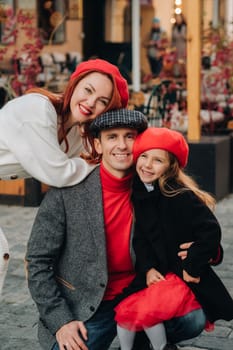 A stylish family of three strolls through the autumn city posing for a photographer . Dad, mom and daughter in the autumn city.