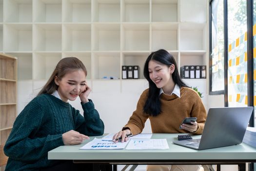 Two beautiful female colleagues interacting while working in office.