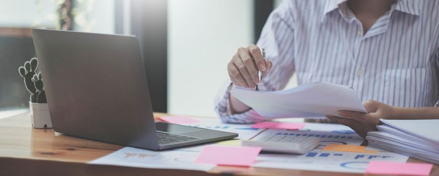 Business woman using calculator for do math finance on wooden desk in office and business working background, tax, accounting, statistics and analytic research concept.