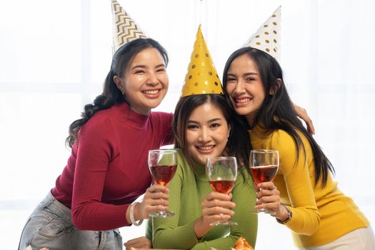 Group of Asian friends gather to celebrate Christmas with champagne and eating pizza at home. Joy of holiday party with friends or colleague concept.