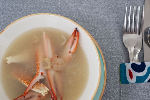 Closeup of crab seafood soup a la carte appetiser starter meal in bowl with cutlery at restaurant table setting
