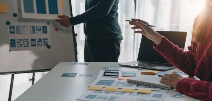 Ux developer and ui designer brainstorming about mobile app interface wireframe design on table with customer breif and color code at modern office.