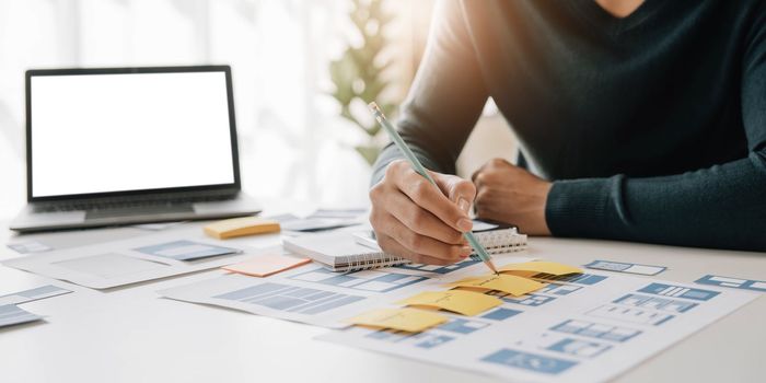 Asian man enjoying on media paperwork design with other office suppliers over sticky notes on the whiteboard. Creative digital development concept