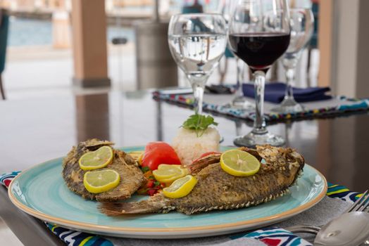 Grilled fish a la carte meal with white steamed rice on plate at restaurant table setting