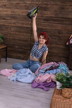 As proof of victory, the young girl lifts the iron up. A smile on her face and inner joy. At home, a wall of brown boards.