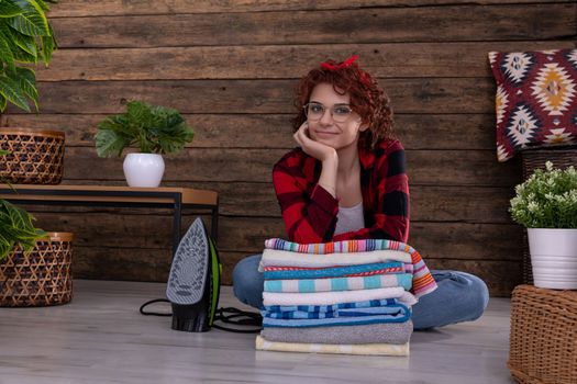 Smiling and full of positive emotions young girl. Towels washed and ironed lie folded in one pile. A European woman with curly hair.