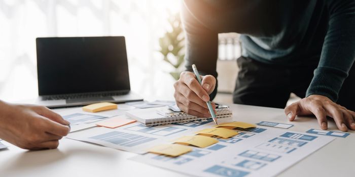 Ux developer and ui designer brainstorming about mobile app interface wireframe design on table with customer breif and color code at modern office.