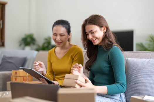 Two women busines startup for online marketing, Entrepreneur packing boxes parcels for shipping, SME sellers, and freelance online sales concept.