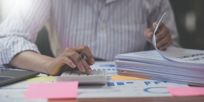 Business woman counting on calculator and holding documents in hands closeup. Bookkeeping concept.